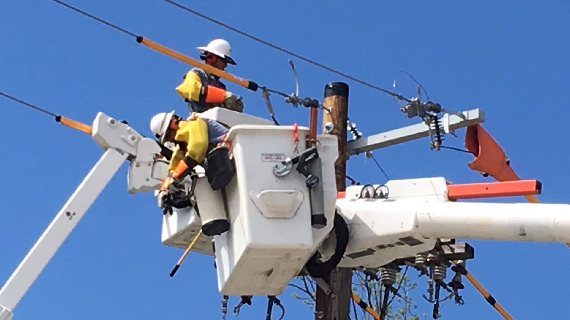 Utility crew in lift-buckets using Sonetics Wireless Headset while performing maintenance on transmission lines.