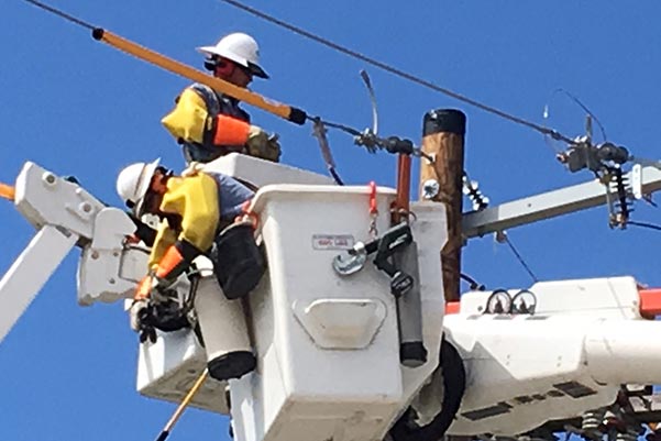 Utility crew in lift-buckets using Sonetics Wireless Headset while performing maintenance on transmission lines.