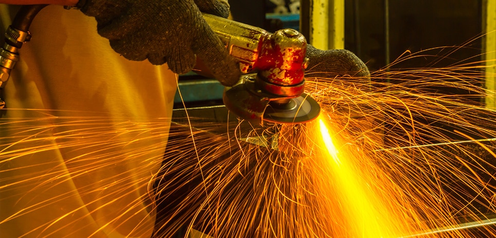 worker grinds steel in factory