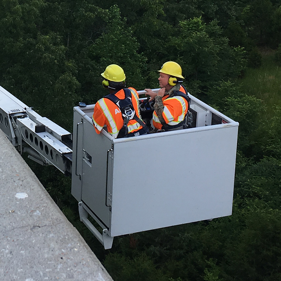 Public Works crew uses snooper truck and Apex Team Wireless Headsets to inspect underneath bridge..