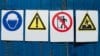 Four warning signs hang on a wall.