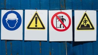 Four warning signs hang on a wall.