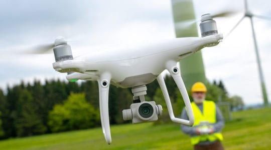 close up of flying drone with operator in background