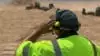 man looking out at worksite wearing cap and noise cancelling headset